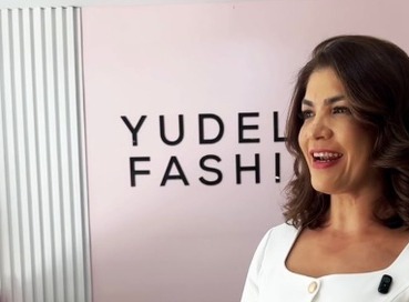 Clienta con un conjunto blanco de peplum frente al panel rosado de la tienda