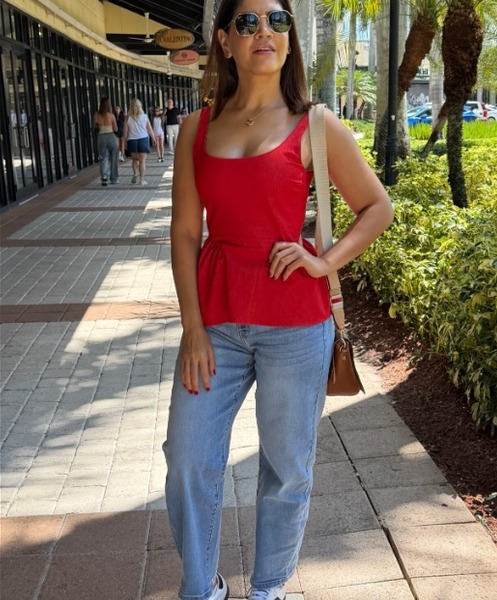 Clienta con top rojo y jeans en una calle con palmeras de Santo Domingo